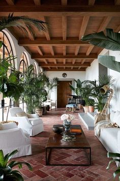 a living room filled with white couches and potted plants on top of them