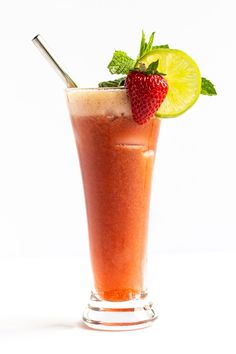 a tall glass with a straw, lime and strawberry on the rim next to a lemon slice