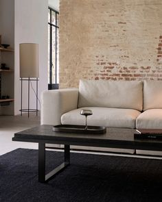 a white couch sitting next to a black table on top of a carpeted floor