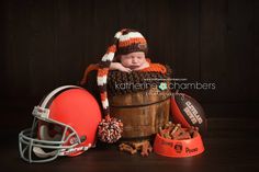 a baby is sitting in a bucket with footballs and other sports items around him