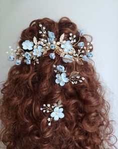 a close up of a woman's hair with blue flowers on it and leaves