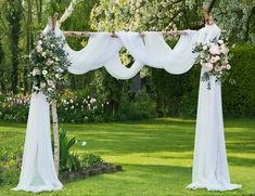 an outdoor wedding ceremony setup with white flowers and draping on the arbors