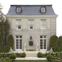 a large house with many windows and bushes around it