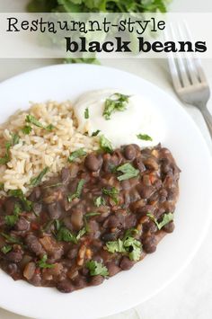 a white plate topped with beans and rice next to a fork, knife and napkin