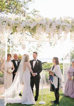 a bride and groom standing under an arch with flowers on it at their wedding ceremony