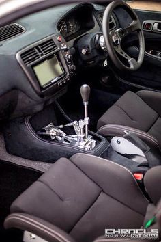 the interior of a car with black leather seats and steering wheel, including an electronic display