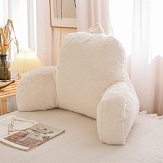 an overstuffed white couch sitting on top of a bed next to a lamp