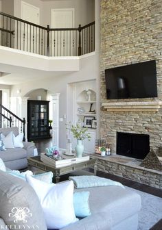 a living room filled with furniture and a flat screen tv mounted on the wall above a fireplace