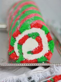 a cake roll decorated with red, green and white icing on a silver platter