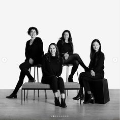 four women are sitting on a bench and posing for a black and white photo in front of a white background