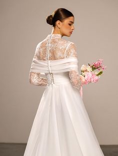 a woman in a white wedding dress holding a bouquet and looking down at the floor