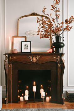 a mantel with candles and pictures on it