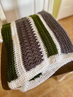 a crocheted blanket sitting on top of a wooden chair next to a door