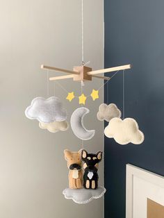 a crib mobile with clouds, cats and stars hanging from it