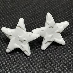 two white star shaped buttons sitting on top of a black surface