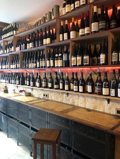 many bottles of wine are lined up on the wall in front of an empty bar