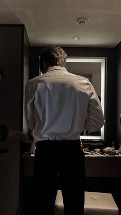 a man standing in front of a bathroom mirror looking at his reflection on the wall