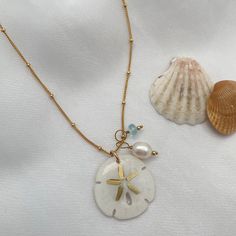 Legend has it that finding a sand dollar during a beach stroll is considered a lucky omen. So take a little bit of the beach and good luck with you wherever you go with our gorgeous Sand Dollar Charm Necklace. Features our most loved satellite chain, freshwater pearl, and blue zircon accents. Freshwater Baroque Pearl size: 6 to 8mm Blue Zircon roundel gemstone 4mm 14kt gold fill or sterling silver round beads 2mm 14kt gold fill or sterling silver satellite chain Real sand dollars are preserved a