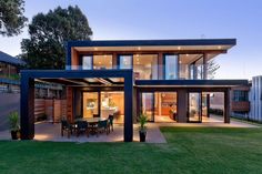 an image of a modern house in the evening time with grass and trees around it