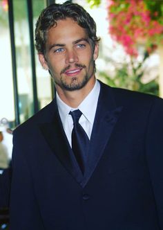 a man wearing a suit and tie standing in front of a window