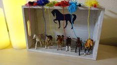 several toy horses in a wooden box with string on the top and one horse standing up