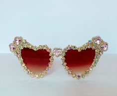 PALE PINK AND AB GOLD JEWELLED EMBELLISHED HEART SHAPED SUNGLASSES. Embellished and encrusted with AB Crystal gold diamanté and pale pink heart shaped rhinestones on a cream based heart shaped sunglasses. All our sunglasses have UV 400 protection.  This is statement decorative eyewear carefully hand embellished for any occasion that requires a bit of extra bling.  Each pair of sunglasses is carefully embellished and handmade by myself and are made to order so please allow two weeks for these to be made and dispatched. CARE All our sunglasses are hand embellished, they take 5 days for rhinestones to set on the frame, and are tested three times before they are posted. However the rhinestones that are encased in a metal claw can fall out if they are not looked after properly. I do add additio Sunglasses Box, Rhinestone Sunglasses, Festival Hat, Shaped Sunglasses, Iridescent Green, Rose Pale, Heart Shaped Sunglasses, Pink Champagne, Pink Rhinestones