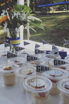 some cupcakes are on a table with flowers in a vase and graduation signs