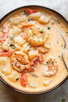 a bowl filled with shrimp and potatoes next to a spoon