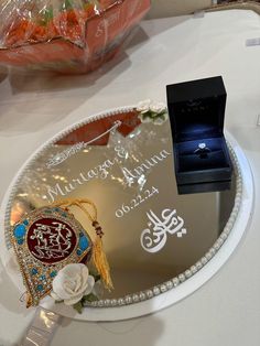 a wedding ring sits on top of a glass plate with flowers and jewelry in it