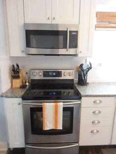 a stainless steel oven and microwave in a kitchen with white cabinets, counter tops, and wood flooring