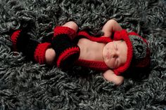 a newborn baby wearing a red and black outfit