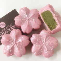 three pink flower shaped soaps sitting on top of a white table next to a black box