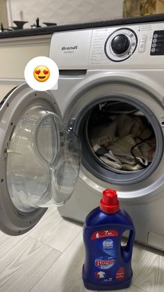 a washing machine with the door open next to a bottle of detergent and a smiley face sticker