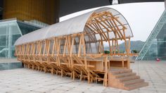 a large wooden structure sitting on top of a tiled floor next to a tall building