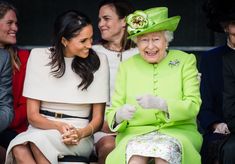 two women sitting next to each other in front of people wearing hats and coats on their heads