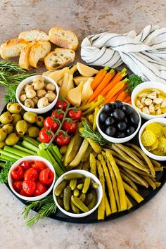 a platter filled with olives, tomatoes, pickles, bread and other foods