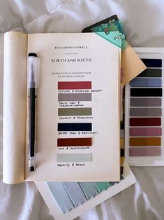 an open book with various colors of paint and a fountain pen on top of it