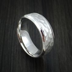 a silver ring with an intricate design on the outside and inside, sitting on a wooden surface