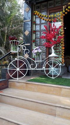 a white bike sitting on top of a set of steps next to a window filled with flowers