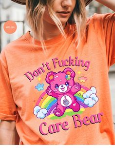 Indulge in rebellious comfort with our "I Don't Care Bear Vibes" T-shirt! This whimsical tee features a cheeky care bear boldly expressing your carefree attitude with a pair of unmistakable middle fingers and a vibrant rainbow backdrop. Crafted from soft, breathable fabric, this shirt guarantees both style and comfort. Embrace the carefree spirit and make a statement with this playful addition to your wardrobe. It's not just a shirt; it's an expression of your "don't give a care" attitude! *Unisex Sizing* Trendy Crew Neck T-shirt With Bear Print, Cute Bear Print Crew Neck T-shirt, Cute Slogan T-shirt For Streetwear, Cute Funny Print T-shirt For Streetwear, Cute T-shirt With Funny Print For Streetwear, Graphic Tee With Bear Print For Streetwear, Trendy Short Sleeve T-shirt With Bear Print, Rainbow Backdrop, Middle Fingers