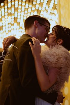 a man and woman are kissing in front of lights