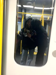 two people standing on a subway train next to each other