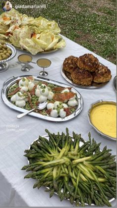 a table topped with lots of different types of food next to green beans and asparagus