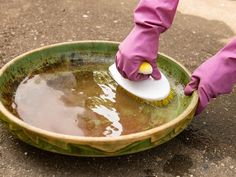 a person in pink gloves is cleaning a green bowl