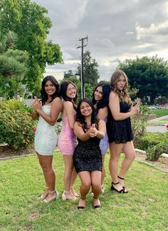 four young women posing for a photo in the grass with their arms around each other