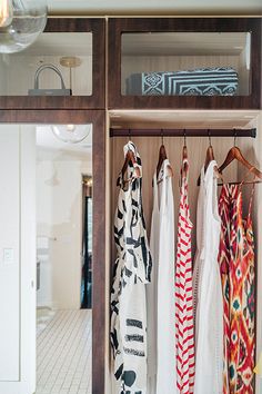 an open closet with clothes hanging on hooks