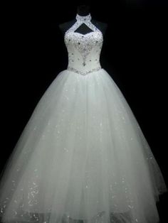 a white wedding dress with beading on the neck and skirt is displayed in front of a black background