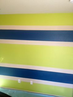 an empty room with green and blue stripes painted on the wall