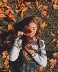 a woman laying on the ground with her eyes closed and holding something in front of her face