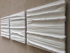 two pieces of white art hanging on the side of a building